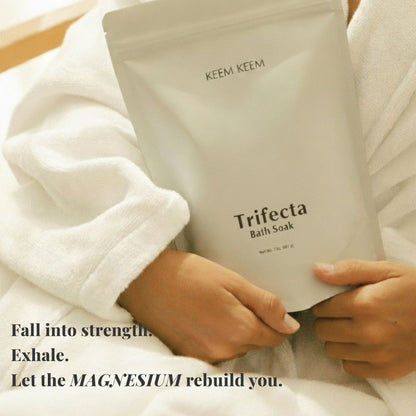Person holding a 'Trifecta Bath Soak' package by KEEM KEEM with text about magnesium benefits.
